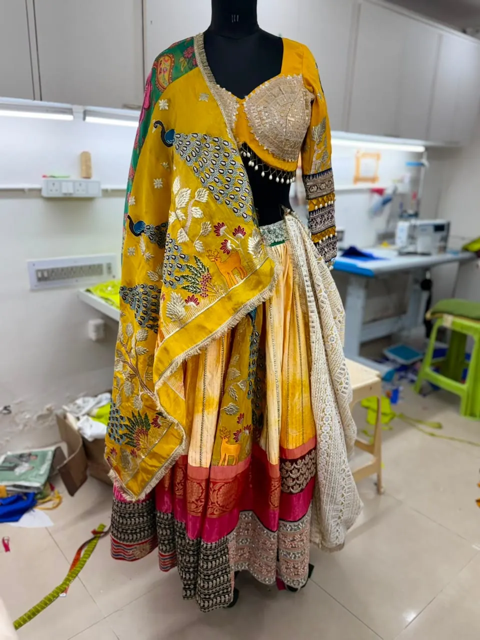 Dusk lehenga workshop reference on mannequin, with yellow dupatta and pink-red hem